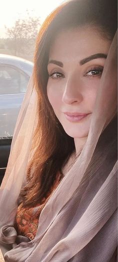 a woman wearing a veil sitting in the back seat of a car on a sunny day