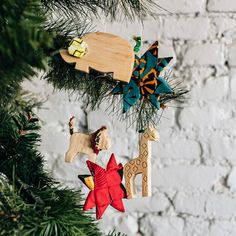 an ornament hanging from a christmas tree next to a brick wall and pine branches