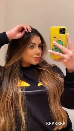 a woman with long hair is holding up her cell phone to take a selfie