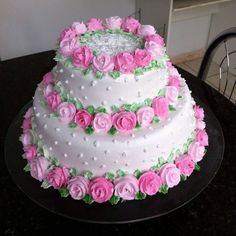 a three layer cake decorated with pink roses