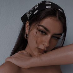 a woman wearing a bandana and posing for the camera with her arm around her neck