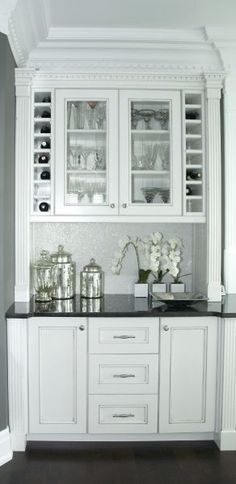 a kitchen with white cabinets and black counter tops in the center, along with dark wood flooring