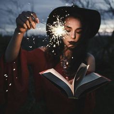 a woman reading a book while holding a sparkler