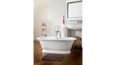 a white bathtub sitting on top of a wooden floor next to a fire place