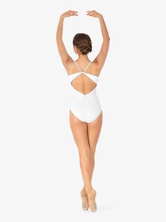 a woman in a white one piece swimsuit is standing with her hands behind her head