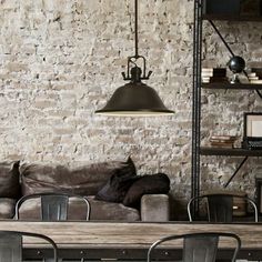 an industrial style living room with exposed brick walls and steel furniture, along with a wooden dining table surrounded by metal chairs