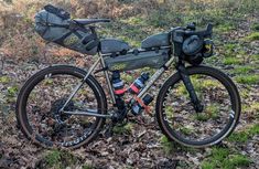 a bicycle parked in the grass with its back pack on it