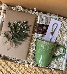 an open box with a green coffee mug and christmas decorations