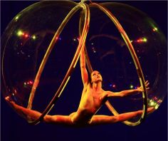 a man is balancing on two large hoops in the air with his hands and feet