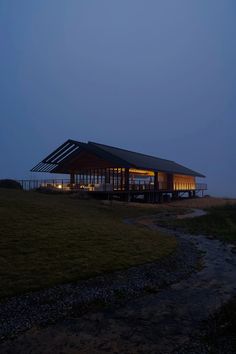 the building is lit up at night with its lights on and grass in front of it