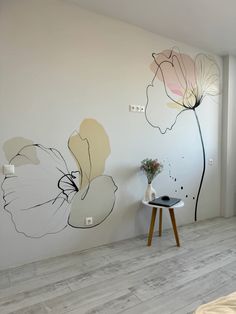 a white room with flowers painted on the wall and a small table next to it