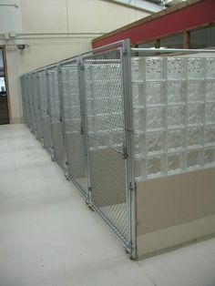 a large metal fence next to a building with glass blocks on the wall behind it