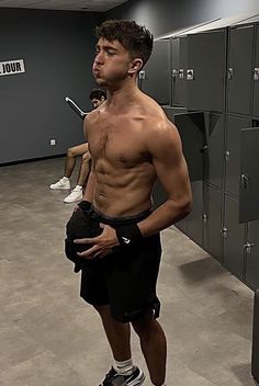 a shirtless man standing in front of lockers with his hands on his hips