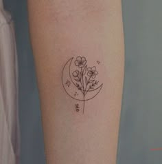 a small flower and moon tattoo on the arm