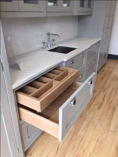 an open drawer in a kitchen next to a sink and counter top with drawers on each side