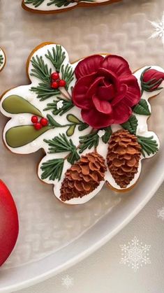 decorated christmas cookies on a plate with holly and pineconi leaves, red ornament