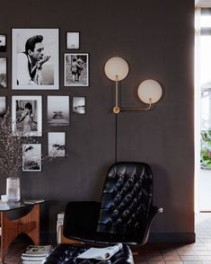 a black chair sitting in front of a wall with pictures on it