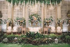 an outdoor wedding setup with flowers, greenery and chandelier hanging from the ceiling