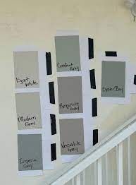 several shades of gray paint are on the wall next to a stair rail with white handrails