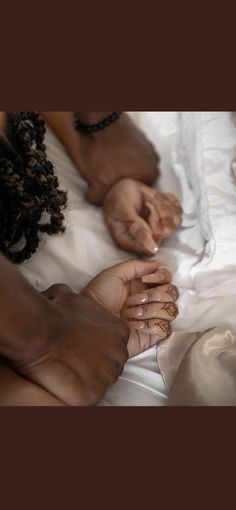 three people are laying on a bed with their hands together and one person is holding the other's hand