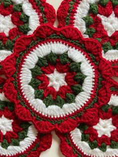 four crocheted coasters with red and white designs on them, all arranged in the same pattern