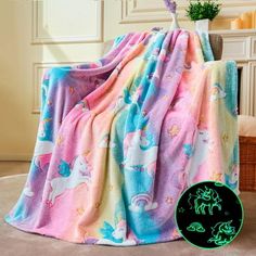 a blanket with unicorns and stars on it in front of a chair next to a potted plant