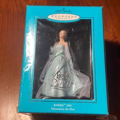 a barbie doll in a blue box on a wooden table