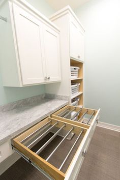 an open drawer in the middle of a kitchen with white cabinets and marble counter tops