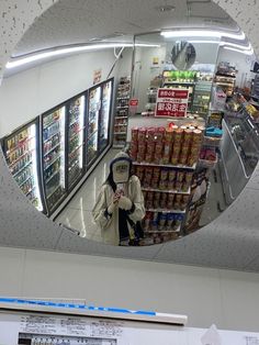 the reflection of a person standing in front of a grocery store's refrigerator door