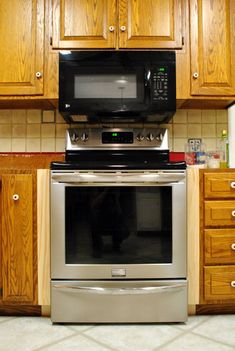 a stainless steel oven and microwave in a kitchen with wooden cabinets on either side of the stove