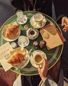 a person sitting at a table with coffee and croissants