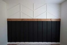 an empty room with white walls and black paneling on the wall, along with wood flooring