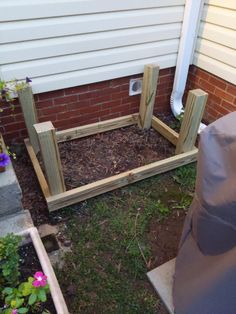 a wooden planter sitting in the middle of a yard next to a brick building