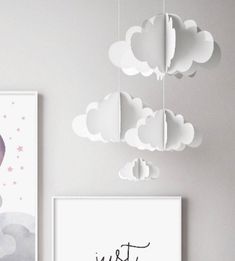 a baby's room with two pictures hanging on the wall and clouds in the ceiling