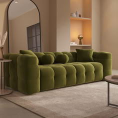 a large green couch sitting in a living room next to a mirror