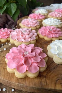 pink and white decorated cookies sitting on top of a wooden cutting board