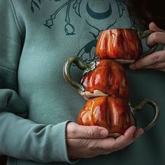 the woman is holding two coffee mugs in her hands, both shaped like snails