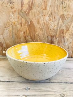 a yellow and white bowl sitting on top of a wooden table