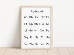 an alphabet poster is displayed on the wall next to a wooden floor and white walls