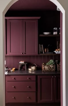 an archway leading into a kitchen with purple cupboards and counter tops in the center