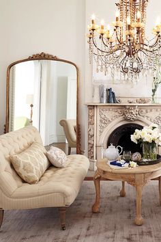 a living room filled with furniture and a chandelier hanging from the ceiling over a fire place