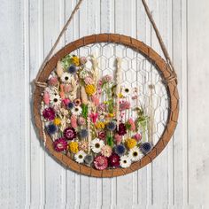 a flower arrangement is hanging on a wall with a wire frame and string around it