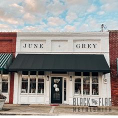 the front of a store with black and white awnings