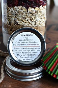 a jar filled with granola, cranberries and oatmeal sitting on top of a wooden table