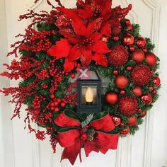 a wreath with poinsettis and christmas decorations hanging on the front door,