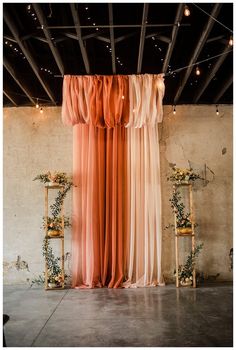 an orange drape is hanging from the ceiling in front of two wooden stools