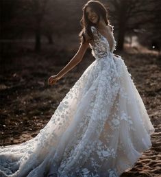 a woman in a white wedding dress standing on the sand