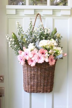 a basket filled with flowers sitting on top of a wooden door sill next to a pink sign