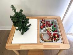 a wooden table topped with a tray filled with christmas decorations