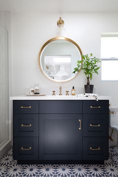 a bathroom with blue and white tile flooring and a round mirror above the sink